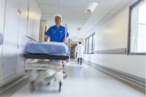 hospital attendant wheeling a patient bed in hallway